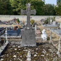 stèle avec croix posée sur une dalle en pierre entourée de piliers metalliques décoratifs avec chaines - nharant