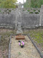 tombe gravillonnée entourée d'une bordurette et surmontée d'une croix en fer ouvragée - natty