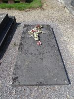 simple pierre tombale grise avec croix fleurie posée, en mauvais état - natty