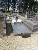 Pierre tombale gris bleutée à gauche dans la concession Deswatine avec gravure en façade et posé dessus un hommage du personnel communal - natty