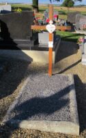 petite tombe gravillonnée avec entourage pierre et croix de bois sur laquelle est fixée une plaque d'identification en forme de coeur, et une plaque avec photo - Natty