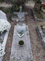 petite dalle grise avec croix scellée sur petit support en pierre. la croix est en métal ouvragé et supporte une plaque d'identification - O.Dufour