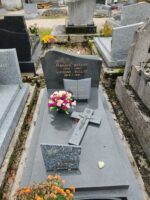 monument gris avec stèle gravée en lettre dorées, une croix est posée sur la dalle 