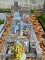 monument gris rosé avec stèle dont la partie gauche est une croix et à droit identification du couple défunt, nombreuses plaques, dont une plaque avec 2 photos posées à l'emplacement de l'espace jardinière en façade - O.Dufour 