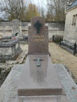 monument gris rosé avec stèle sur laquelle est fixée une croix noire avec une tête de christ sous laquelle figure l'identification. le monument possède de larges margelles et une croix est posée sur la pierre tombale - O.Dufour