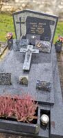 monument gris bleu, avec stèle fond claire sur laquelle est dessiné un parchemin gris foncé avec l'identification des défunts et à gauche une croix de même teinte. Espace jardinière en façade - nharant