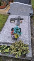 monument gris moucheté avec stèle gravée et espace jardinière en façade, une croix est posée sur la pierre tombale - nharant