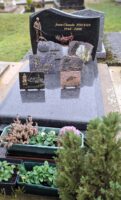 monument de couleur grise avec stèle noire sur laquelle est gravée l'identité du défunt, et à gauche est représenté un chasseur avec son chien - nharant