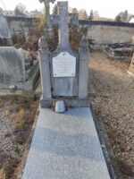 pierre tombale grise avec stèle ouvragée en pierre (encadrée de 2 piliers ronds surmontés d'une boule ovale, et croix au centre) su laquelle est fixée une plaque d'identification blanche - O.Dufour