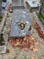 Pierre tombale grise dont un coin est cassé, avec écusson identification et petite croix ornée de roses - O.Dufour