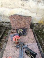 monument moucheté rose et noir avec stèle sur laquelle est gravée une croix dorée à gauche de l'identification - O.Dufour