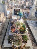 Petite tombe en pierre avec stèle sur laquelle est fixée une plaque d'identification noire, et espace jardinière en façade - O.Dufour