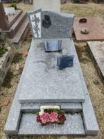 monument gris moucheté avec stèle sur laquelle figure à gauche de l'inscription une tête de la vierge et de Jesus christ et une croix avec feuillages entrelacés - O.Dufour