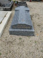 monument gris foncé moucheté avec Croix incrustée sur la pierre tombale et identification en façade