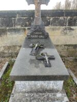 monument surélevé en pierre grise surmonté d'une croix en pierre à la base de laquelle figure l'identification- 2 crucifix sont posés sur la pierre tombale - O.Dufour