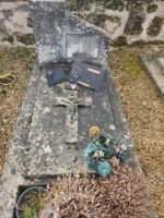 pierre tombale grise en mauvais état avec croix posée dessus et stèle sur laquelle est fixée une plaque d'identification - O.Dufour