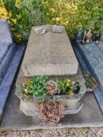 Monument en pierre grise, surélevé, avec gravure sur la pierre tombale, et jardinière en façade - o.Dufour