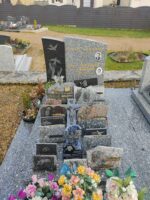 monument gris moucheté avec stèle partie droite même couleur grravée, et partie gauche noire avec deux mains tendues vers 2 colombes - O.Dufour