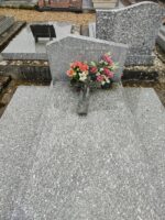 monument gris moucheté avec stèle gravée et larges semelles latérales. une croix est posée sur la pierre tombale - O.Dufour