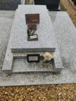 pierre tombale gris moucheté avec larges semelles latérales et une plaque blanche entourée de noir posée dans l'espace jardinière - O.Dufour