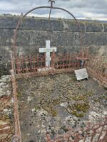 dalle en pierre entourée par une grille ouvragée et surmontée d'un arceau. Croix blanche et plaque mort pour la France - O.Dufour