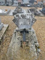 petite tombe en pierre avec stèle forme éventail sur laquelle est fixée une plaque d'identification. Croix sur la pierre tombale - O.Dufour