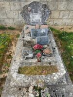 petite tombe en pierre avec stèle sur laquelle est fixée une plaque d'identification et une photo de l épouse. La photo de l'époux figure sur une plaque posée sur la pierre tombale. - O.Dufour
