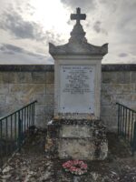 très grande stèle carrée avec croix au dessus, posée sur une grande dalle et entourée d'une grille. le nom des défunts figure sur les 3 côtés de la stèle - O.Dufour