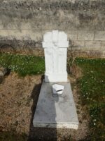 petite tombe d'enfant avec stèle blanche posée sur la pierre tombale. sur la stèle figure une croix gravée avec des visages d'anges - O.Dufour