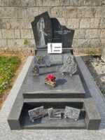monument gris foncé avec stèle noire ou figure l'identification en lettres blanches et à gauche une jeune femme avec une fleur - O.Dufour