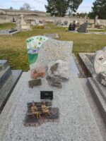 monument gris moucheté avec stèle sur laquelle figure l'identification en lettres dorées, et à gauche une peinture représentant un village avec son clocher - o.Dufour 