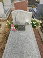 monument gris clair moucheté avec stèle sur laquelle est fixée une croix à gauche - O.Dufour