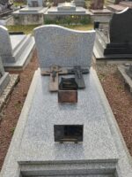 monument gris moucheté avec stèle gravée en lettres dorées. deux croix posées sur la pierre tombale - O.Dufour