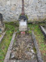 petite tombe entourage pierre avec petite stèle sur laquelle est fixée une plaque d'identification. Elle est surmontée d'une croix en métal ouvragé - O.Dufour