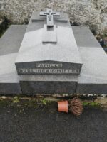 large monument gris avec pierre tombale centrale sur laquelle est sculptée une croix, et en façade l'identification de la famille.