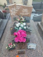 monument moucheté rose et gris avec stèle sur laquelle figure une fleur blanche à gauche de l'identification en lettres blanches - O.Dufour