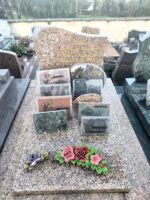 monument moucheté rose et gris avec stèle gravée en lettres dorées, à Gauche d'une fleur blanche - O.Dufour