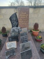 monument moucheté gris et bordeaux avec , à droite, grande stèle gravée en lettres dorées, et à gauche petite stèle avec fleurs blanches sur fond noir - O.Dufour