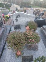 monument gris moucheté avec stèle gravée en lettres blanches à droite d'une fleur noire - O.Dufour 